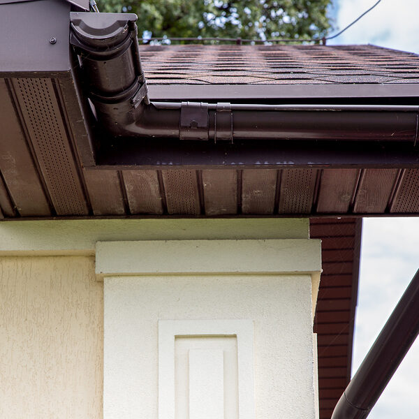 Brown Plastic Drainage Gutter On A Roof With Bituminous Tiles Cl Rain gutter guard installation in Greeley and Northern Colorado.